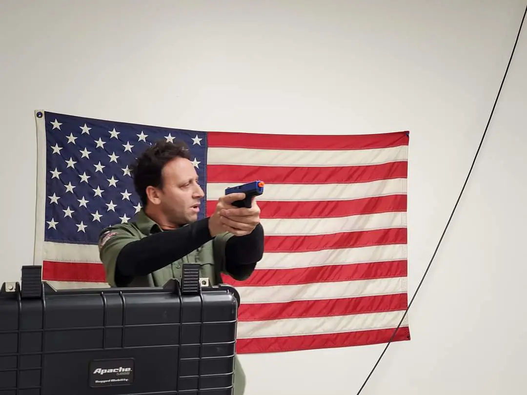 A man holding a remote control in front of an american flag.