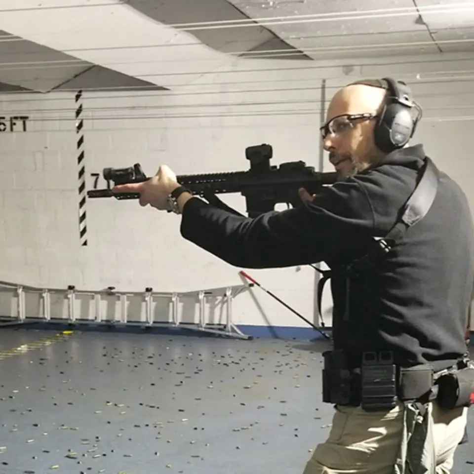 A man in black jacket holding a rifle.