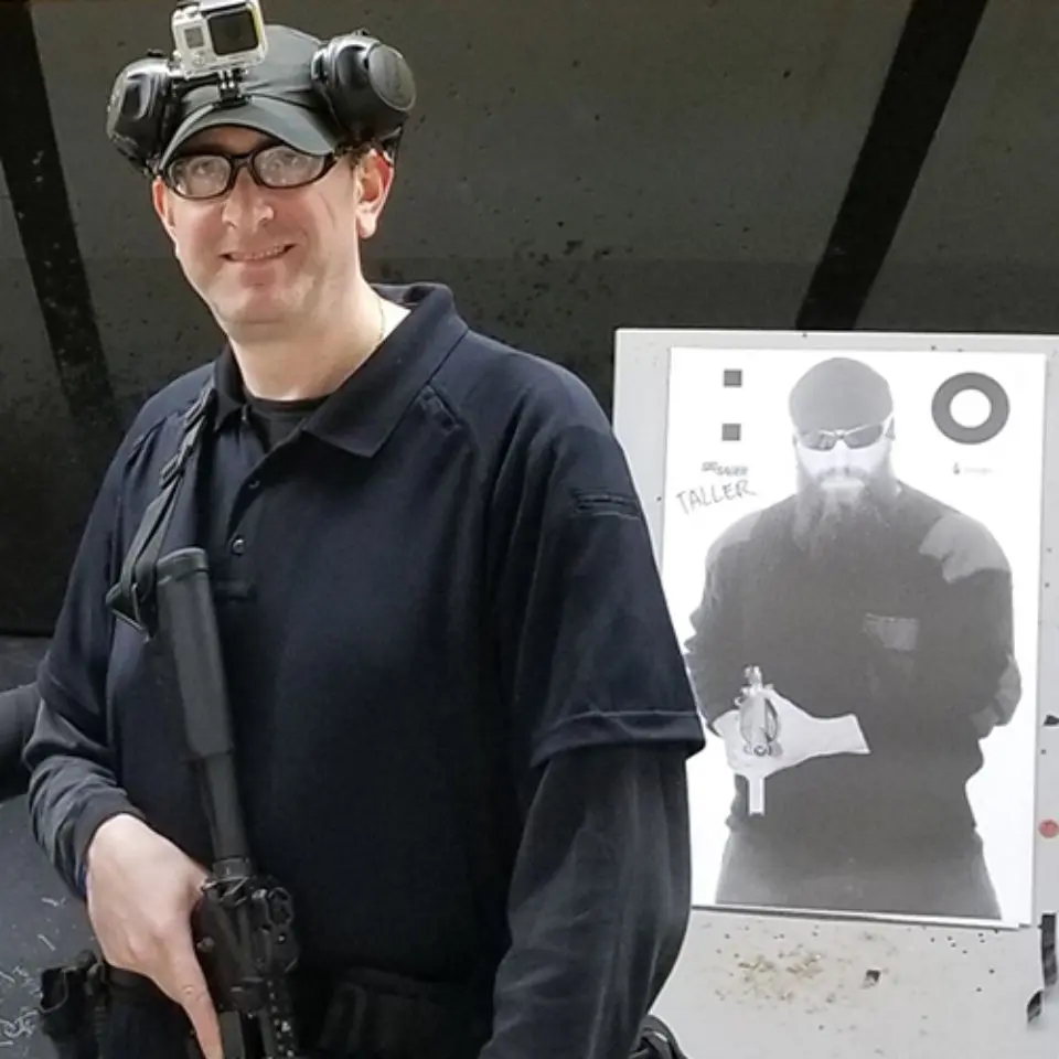 A man holding an ar-1 5 rifle in front of a target.