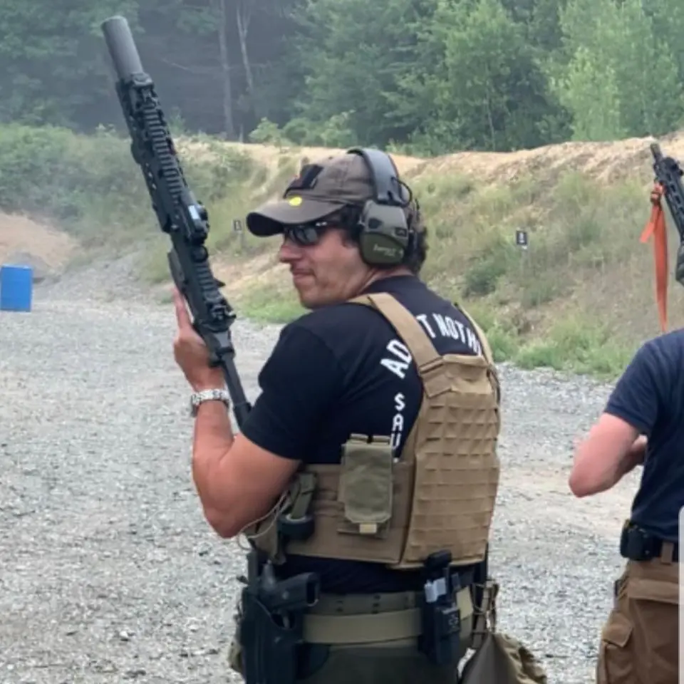 A man holding a rifle while wearing ear muffs.