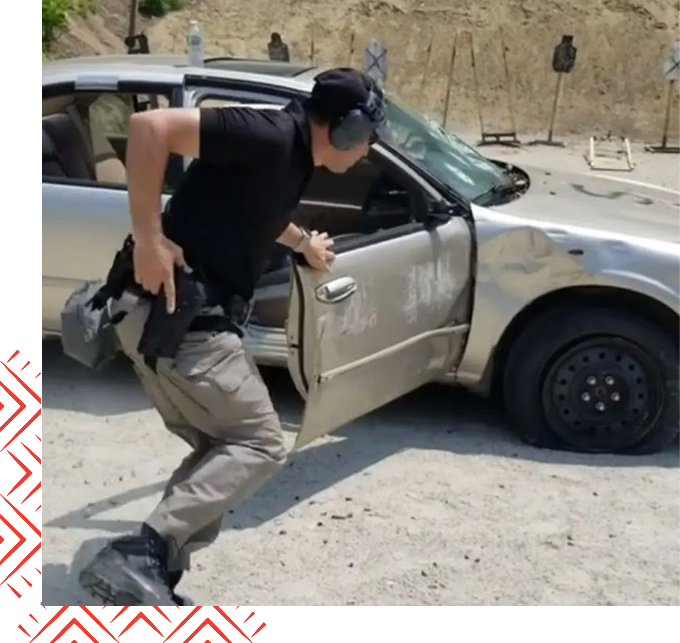 A man in black shirt and helmet running out of car door.