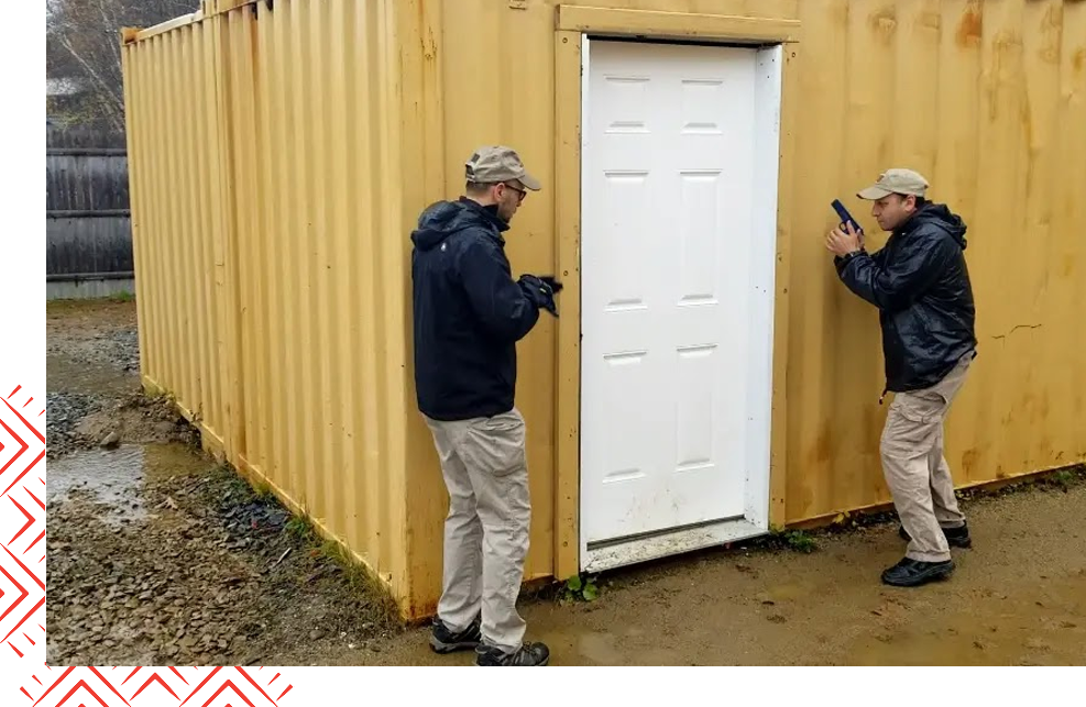 Two men standing outside of a building with doors open.